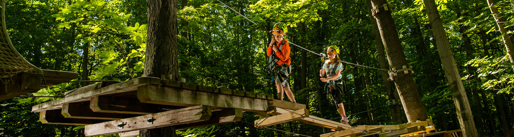 One boy and one girl on an adventure course walking on wooden planks